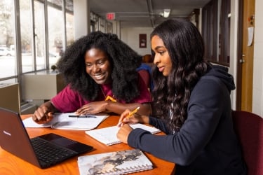 Two SIUC students working on laptop together